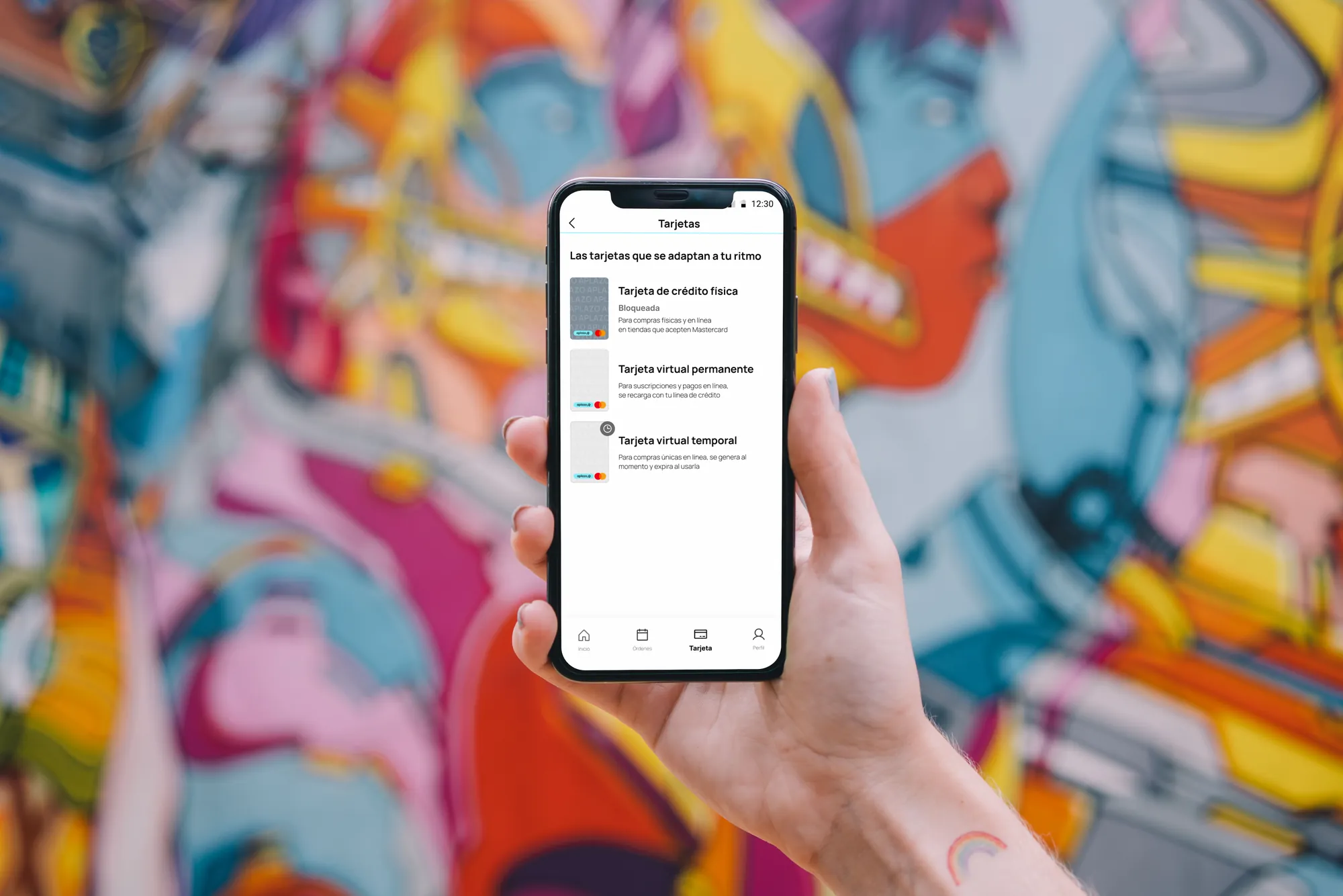 Aplazo cards screen in hand against a colourful mural