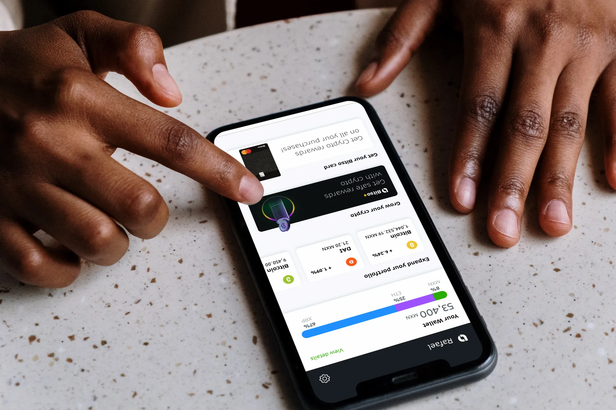 Finger tapping the Bitso wallet on a terrazzo table